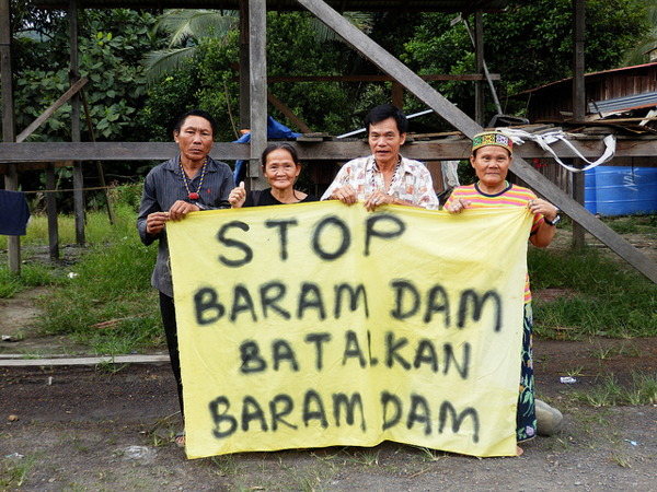 Members of the Penan indigenous group carry a sign stating their opposition to the proposed Baram Dam in Sarawak, Malaysia, in February 2014. Many indigenous communities oppose the dam, which will displace between 6,000 and 20,000 people, according to various estimates. Photo credit: International Rivers.