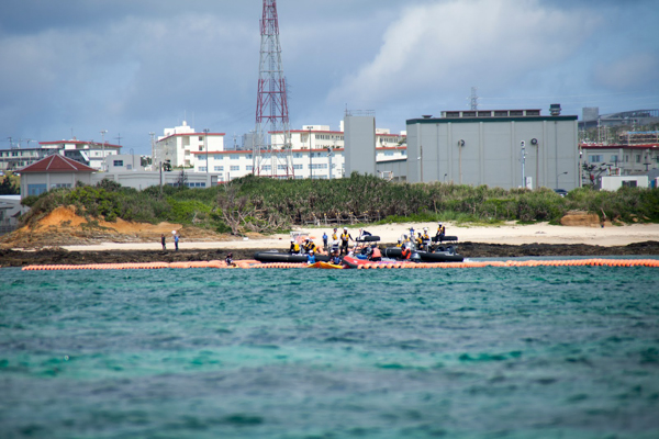 Japanese coast guard vessels approach kayakers near the US base Camp Schwab, where the new US airstrip is planned, on May 17, 2015. The kayakers are protesting construction of the airstrip. Photo credit: ©Greenpeace / Kayo Sawaguchi.